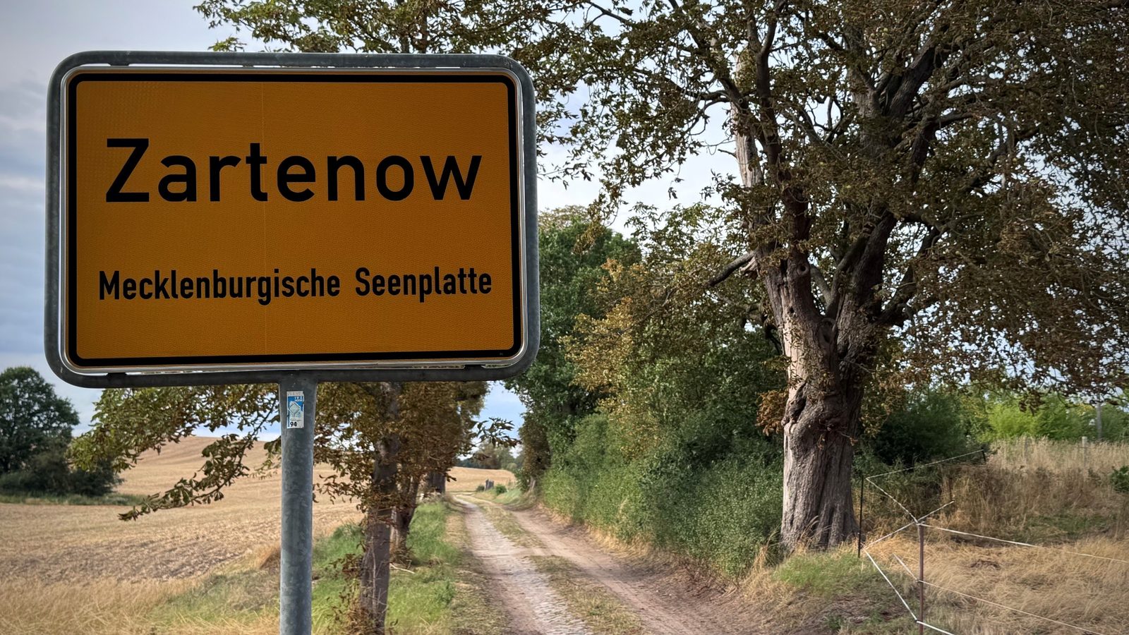 Ortsschild Zartenow, Mecklenburgische Seenplatte, an einem Feldweg mit Kopfsteinpflaster, daneben eine alte Eiche